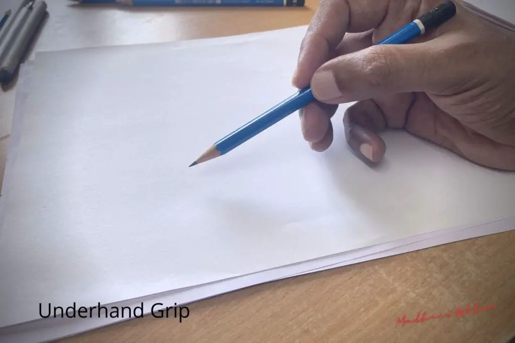 a hand holding a pencil with underhand grip on plain white paper , showing how to hold a pencil when drawing