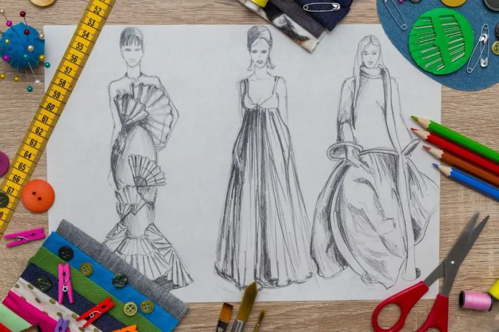 Image of three Fashion illustration drawing with tape, pencils, scissors, brushes and other drawing and sewing things around