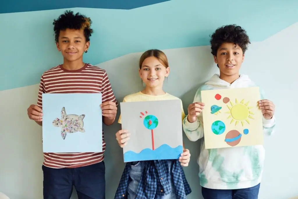 three-young-students-showing-their-artwork