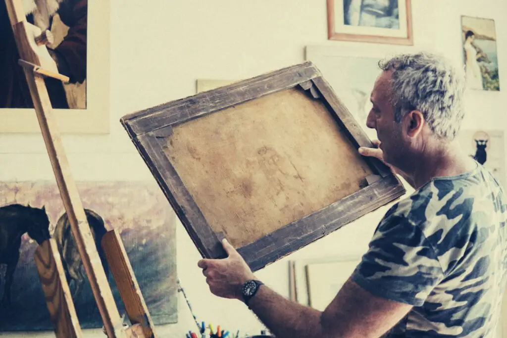 An artist checking the backside of the frame of an old painting