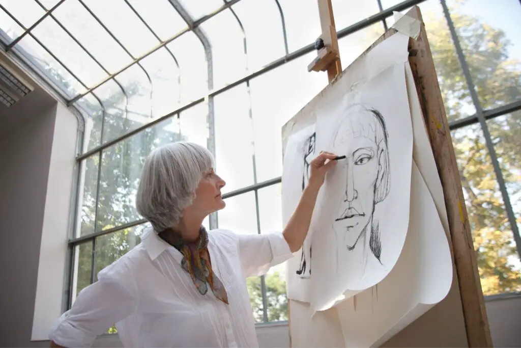 A female artist drawing a face on a chart paper with charcoal
